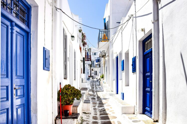 Charming whitewashed alley with blue doors in Mykonos, Greece, a perfect 30th birthday travel destination.