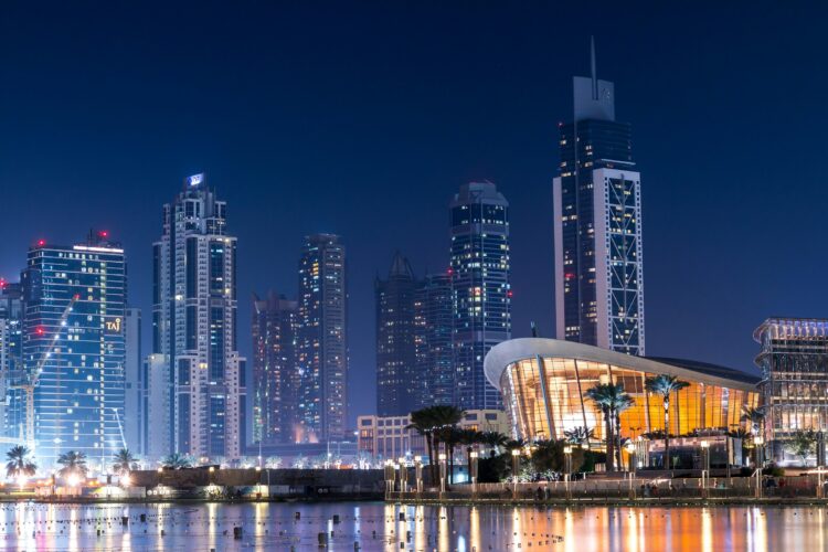 Dubai skyline at night with illuminated skyscrapers and modern architecture reflecting on the water.