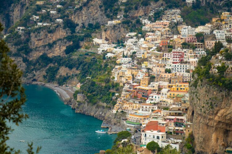 Scenic view of Positano, Italy, featuring colorful cliffside buildings, a turquoise sea, and lush Mediterranean landscapes on the Amalfi Coast.