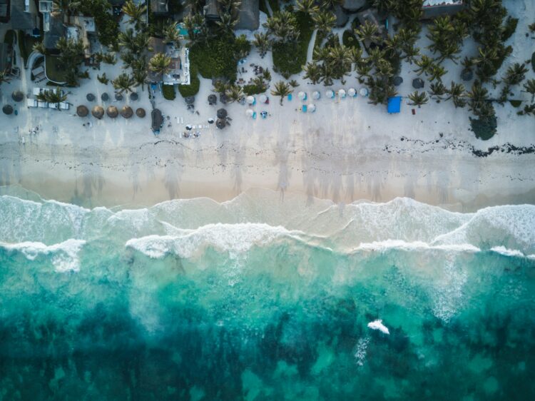 Aerial view of Tulum’s pristine white-sand beach and turquoise waters, lined with palm trees and luxury beachfront resorts—perfect for a 30th birthday getaway.